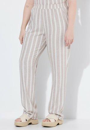 Beige und weiß vertikal gestreifte, lockere Hose mit elastischem Bund, getragen mit beigen Plateausandalen an einer stehenden Person.