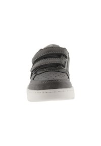 Zapatilla gris con un upper suave y perforaciones, tres correas de Velcro ajustables y una suela de goma blanca.
