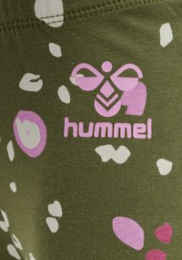 Grön tyg med en texturerad yta, med abstrakta rosa och vita former. Inkluderar varumärkeslogotypen "hummel" i rosa.