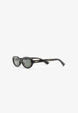 Okrągłe czarne okulary przeciwsłoneczne z zielonymi szkłami, wyrazistą plastikową oprawką i smukłymi zausznikami z delikatnymi marmurkowymi akcentami. Minimalistyczny design.