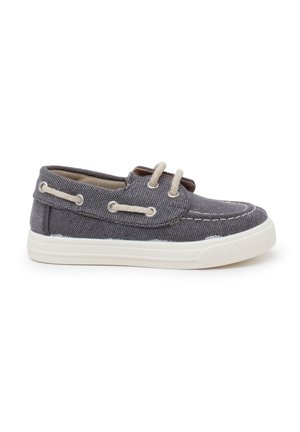 Scarpa da barca in tela grigia con suola in gomma bianca, dotata di lacci e occhielli in un tono beige chiaro. Subtle motivo testurizzato sul materiale superiore.