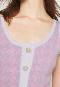 Cardigan a maglia di colore lilla e rosa con un motivo testurizzato, caratterizzato da una patta centrale con bottoni decorativi simili a perle.