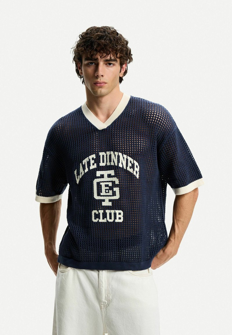 Maglione corto a maniche corte in rete di colore blu navy con scollatura a V e bordo crema a contrasto; caratterizzato da grafica "LATE DINNER CLUB" in bianco.