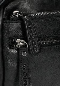 Borsa in pelle nera con hardware argentato, chiusura a zip dettagliata, logo in rilievo sulla tracolla e texture liscia. Presenta numerosi scomparti.