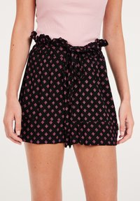 Pantaloni corti neri con un design a fantasia caratterizzato da piccoli diamanti rosa, una vita arricciata e un dettaglio di fiocco annodato sulla parte anteriore.
