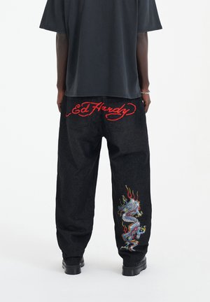 Czarne dżinsy z czerwonym haftowanym logo "Ed Hardy" i kolorowym wzorem smoka na lewej nogawce. Dopasowany krój z minimalnymi detalami.
