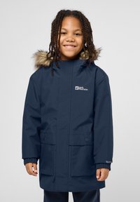 Parka impermeabile blu marina con cappuccio in pelliccia sintetica, tasche frontali, polsini elasticizzati e logo stampato sul petto. Tessuto resistente e vestibilità ampia.