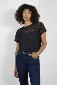 Black top featuring lace short sleeves and an inset lace panel. Paired with dark jeans and a black belt for a casual look.