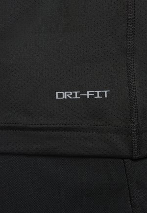 Tejido atlético DRI-FIT negro con superficie texturizada. Presenta un logo rectangular en gris, costuras cosidas y secciones de malla transpirable.