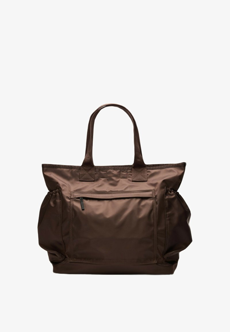 Sac fourre-tout en nylon marron avec doubles poignées, une poche zippée à l'avant et deux poches latérales sur fond blanc.