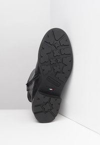 Black leather boot with a textured rubber sole featuring a patterned tread and zipper closure on the side. Stamped brand details included.