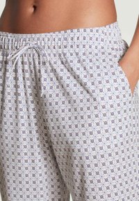 Lichte, gemusterde loungebroeken met een elastische tailleband, trekkoord en zakken; beschikt over een blauw-paarse bloemenprint op een witte stof.