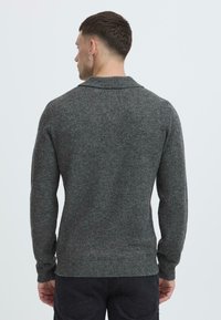 Grau gestrickter Pullover mit Schalkragen, gerippten Bündchen und Saum; aus weichem, strukturiertem Material gefertigt, zeigt ein glattes, tailliertes Design.