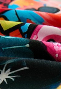 Tessuto colorato con motivi grafici, inclusi toni di blu, rosa, nero e giallo. Superficie texture con una sensazione morbida e liscia.