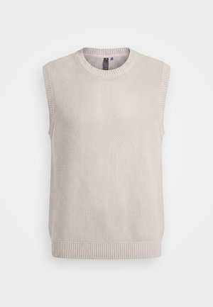 Ανοιχτό μπεζ πλεκτό γιλέκο χωρίς μανίκια με ριμπ λαιμόκοψη σε στρογγυλό σχήμα, μασχάλες και τελείωμα, εμφανιζόμενο σε λευκό φόντο.