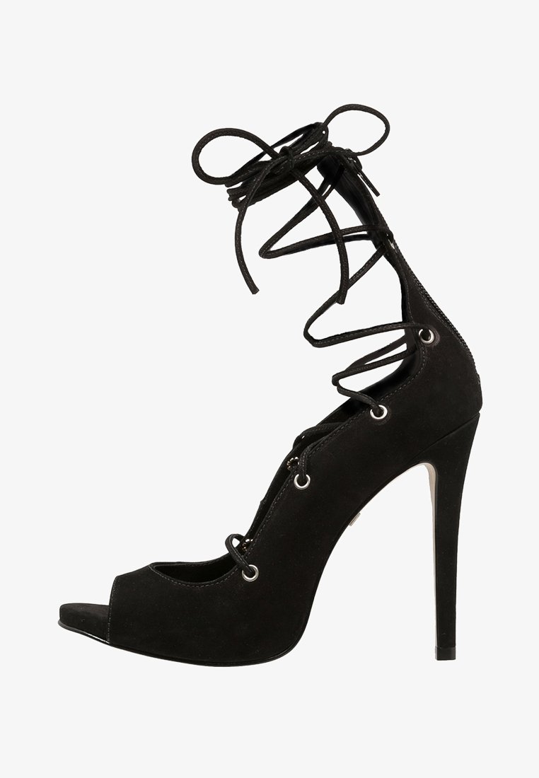 Sandale à talons hauts en suede noir avec un bout ouvert et des lanières à lacets qui s'enroulent au-dessus de la cheville.