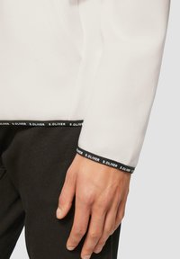 Witte sweatshirt met een zwarte elastische band met de tekst "S. OLIVER" aan de onderkant, met een soepele textuur en een ontspannen pasvorm.