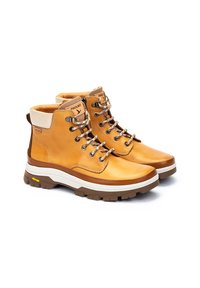 Botas de senderismo de cuero marrón con suela de goma blanca y marrón. Las características incluyen ojales de metal, un collar beige y un diseño de cordones texturizado.