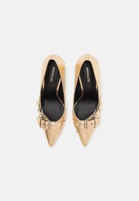Gold-toned high-heeled shoes with a pointed toe and buckle accent. Glossy texture and a sleek design enhance their elegance.