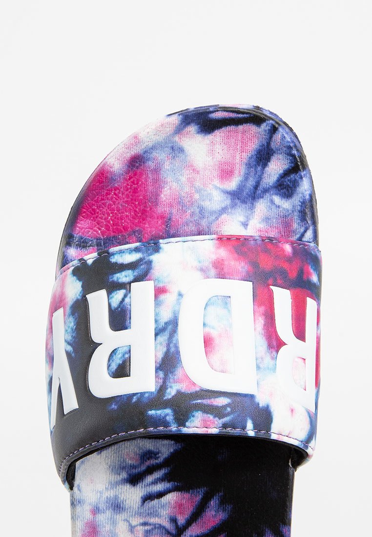 Rutschsandale mit einem Batikmuster in Pink, Lila und Blau. Verstellbarer schwarzer Riemen mit fettem weißen Text. Weicher Stoff mit angenehmer Haptik.