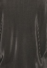 Tessuto plissettato nero con sottili strisce verticali, texture liscia e finitura lucida, che crea un aspetto moderno e dinamico.