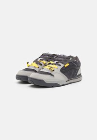 Gray and black sneakers with yellow laces, featuring a mix of suede and mesh materials, rounded toe, and subtle perforated detailing.