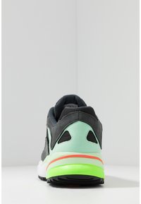 Urheilukengät, joissa on musta mokkanahkainen päällinen, mintunvihreät yksityiskohdat, verkkopaneelit ja uurretusta kumipohjasta, jossa on neonpinkin ja -vihreän värinen välipohja.