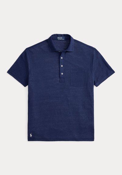 Μπλε ναυτικό πόλο με υφή υφάσματος, με γιακά, πατιλέτα με τρία κουμπιά και τσέπη στο αριστερό στήθος. Μικρό λογότυπο στο τελείωμα.