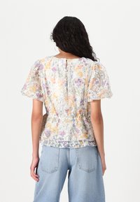 Blomstrete gjennomsiktig bluse med pufferm, pastellfarger, rynket midje, og en nøkkelhulåpning bak. Kombinert med lyse denimjeans.