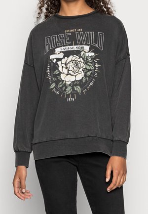 Sudadera gris oscuro con un gráfico floral en blanco y verde, y texto "ROSE WILD". Corte holgado y mangas largas. Textura suave.