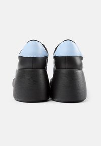 Schwarze und hellblaue Lederschuhe mit abgerundetem Zehenbereich, erhöhtem, strukturierten schwarzen Absatz und kontrastierenden Nähdetails auf dem Obermaterial.