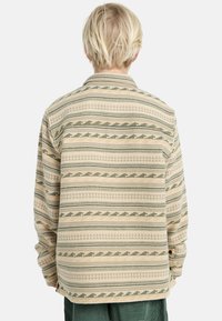 Camicia beige a fantasia con strisce geometriche verdi. Presenta un colletto e maniche lunghe, realizzata in tessuto texture.