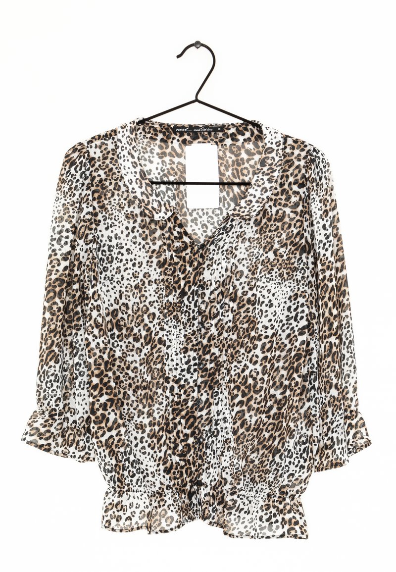 Blouse à manches longues imprimée léopard avec poignets et ourlet à volants, boutonnée devant avec un petit col, suspendue sur un cintre noir sur fond blanc.