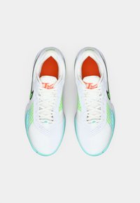 Et par hvide sportsko med grønne og teal accenter, orange indvendig foring og sorte Nike swoosh-logoer, set ovenfra.