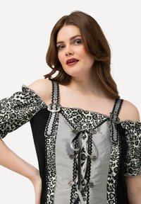 Schwarzes Kleid mit schulterfreien Leopardenmuster-Ärmeln, silbernen Akzenten und einer Schnürfront, die mit gemustertem Stoff und dekorativem Zubehör versehen ist.