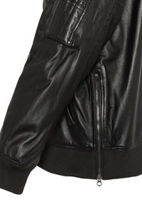 Veste en cuir noir avec une texture lisse, des poignets côtelés, une fermeture éclair sur le côté et une poche à patch sur la manche pour un détail supplémentaire.