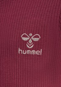 Burgundowy żeberkowany materiał z haftowanym jasnoszarym logo z stylizowaną pszczołą i napisem "hummel" poniżej.