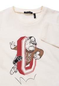 Cremfarbener T-Shirt mit einem grafischen Design, das einen Bulldoggen mit einem Hut zeigt, umrandet von einem roten "O" und braunen Akzenten.