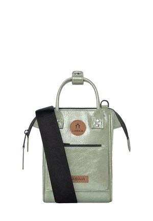 Green patent leather tote bag with a top handle, zippered closure, front pocket, and adjustable black strap. Features a logo patch.