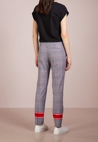 Top corto nero a maniche corte abbinato a pantaloni grigi a quadri con risvolti a righe rosse e bianche. I pantaloni hanno una vestibilità attillata e una tasca sul retro.
