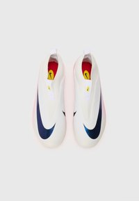 Baskets blanches à enfiler avec une texture lisse, présentant un logo Nike en bleu foncé, des accents jaunes et une semelle translucide rose.