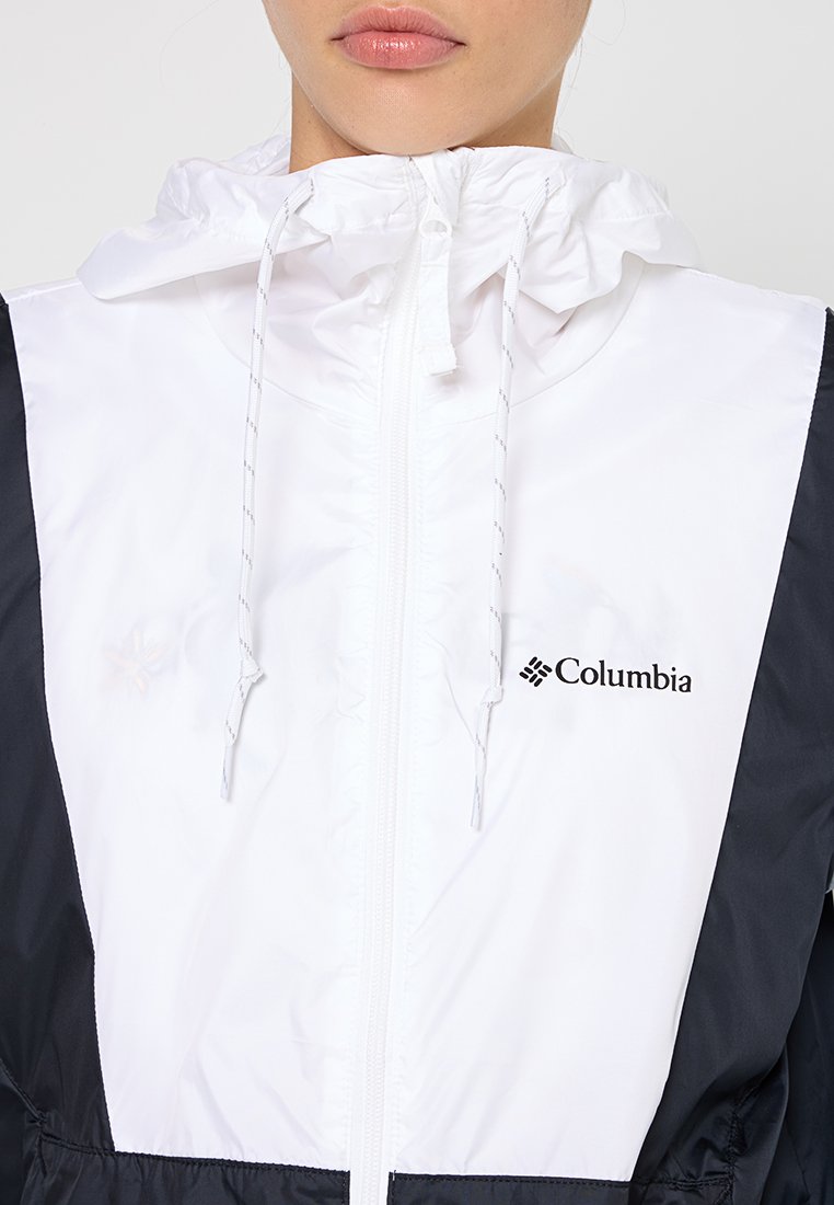 Chaqueta con capucha blanca y negra, con cierre de cremallera, cordones y logo de Columbia. Material suave y ligero con un diseño contrastante.