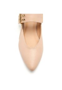 Zapato de piel nude con punta afilada y diseño con cortes, que presenta una amplia correa en el tobillo con herrajes dorados y cortes circulares.