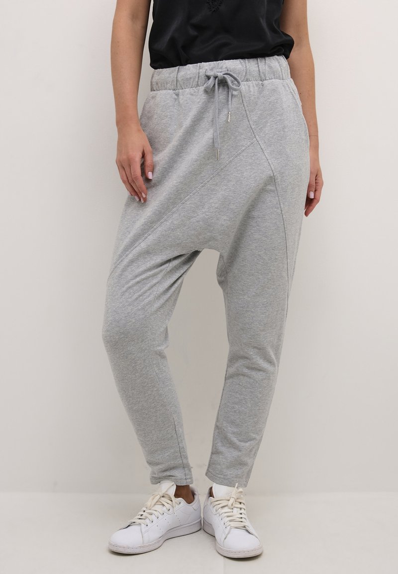 Svetlé šedé joggers so zúženým strihom vyrobené z mäkkej, ľahkej tkaniny s elastickým pásom a šnúrkou. Obsahuje bočné švy a manžety na spodnom okraji.