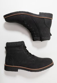 Bottines noires à cheville avec un dessus en cuir lisse, un col en tissu texturé, une semelle en caoutchouc et une fermeture éclair sur le côté. Présente des coutures accentuées en brun.