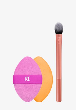 Pinceau de maquillage avec une tête en poils roses et noirs et un manche en cuivre, accompagné d'un applicateur en mousse rose et d'une éponge orange.