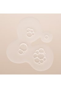 Des bulles claires et brillantes en grappes sur une surface lisse de couleur beige clair, de tailles variées avec des formes rondes et des surfaces réfléchissantes.