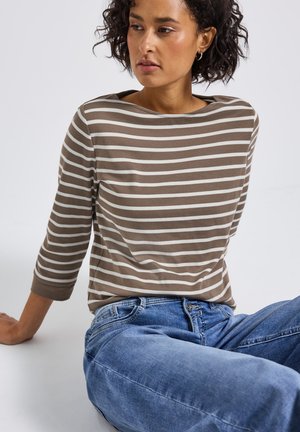 Bruin en wit gestreepte longsleeve-top met een bootnek, gecombineerd met lichtblauwe rechte jeans, zittend tegen een neutrale achtergrond.