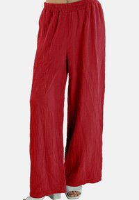 Løse, vid-benede røde bukser lavet af tekstureret stof med elastisk talje, der har et krøllet mønster for ekstra visuel interesse.