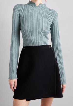 Geribbelde turquoise lange mouw top met hoge kraag en zwarte wikkelrok met zijknopen, gladde textuur en getailleerd ontwerp.